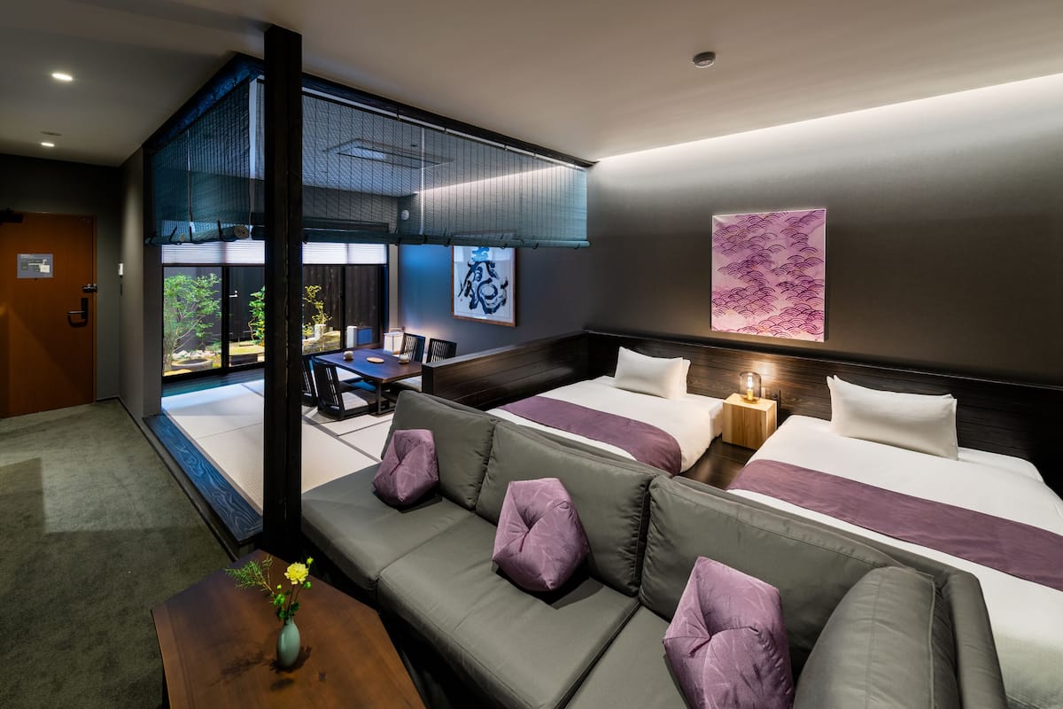 Een moderne hotelkamer met een groot bed, een zithoek, een eethoek en uitzicht op het groen.