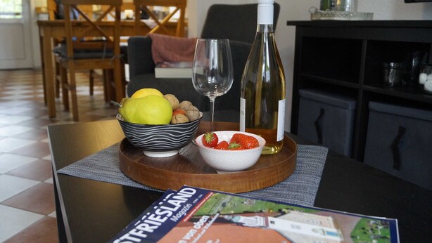 Un tavolo da pranzo con una ciotola di frutta, una bottiglia di vino e un bicchiere da vino.