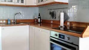Una cucina con mobili bianchi, un forno in acciaio inossidabile e uno schienale piastrellato.