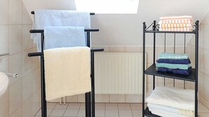 A bathroom with a skylight, a towel rack, and a shelf with folded towels. - Ferienwohnung Verklicker - Ferienwohnungen im Haus am Watt in Ostbense (Neuharlingersiel)
