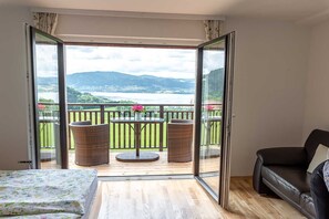 A room with a bed, a sofa, a balcony with wicker chairs, and a table with flowers. - Tilda - Schöbringer Farm (Miglberg)