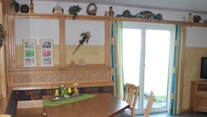 A dining area with a wooden table, chairs, a bench, and a decorative wall with framed pictures.