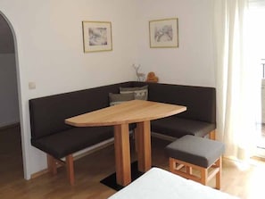 A living room with a dark-colored sofa, a wooden table, and a small wooden stool. There are two framed pictures on the wall. - Tilda - Schöbringer Farm (Miglberg)