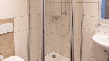 Une salle de bain avec une douche à parois de verre, un lavabo blanc et des toilettes.