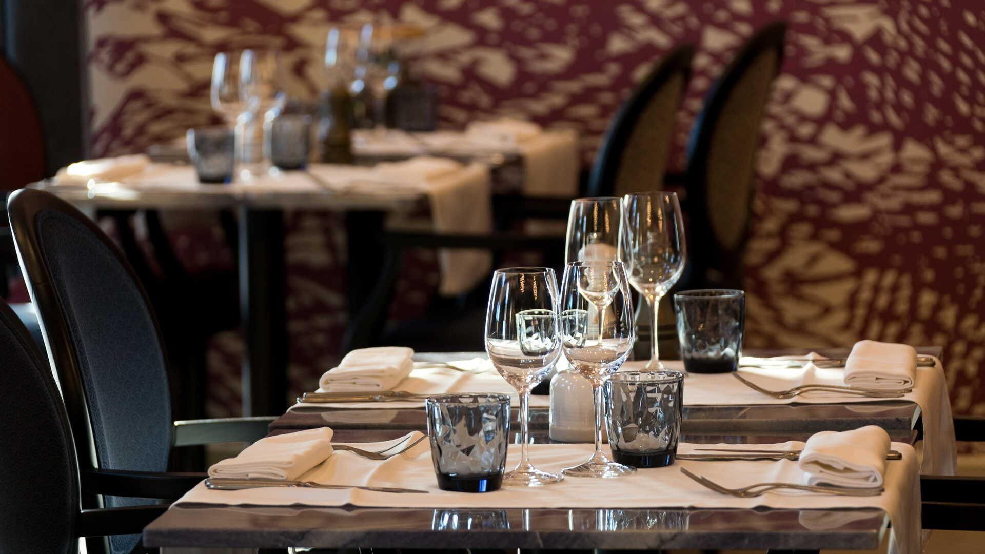A restaurant table set with wine glasses, water glasses, and a folded napkin.