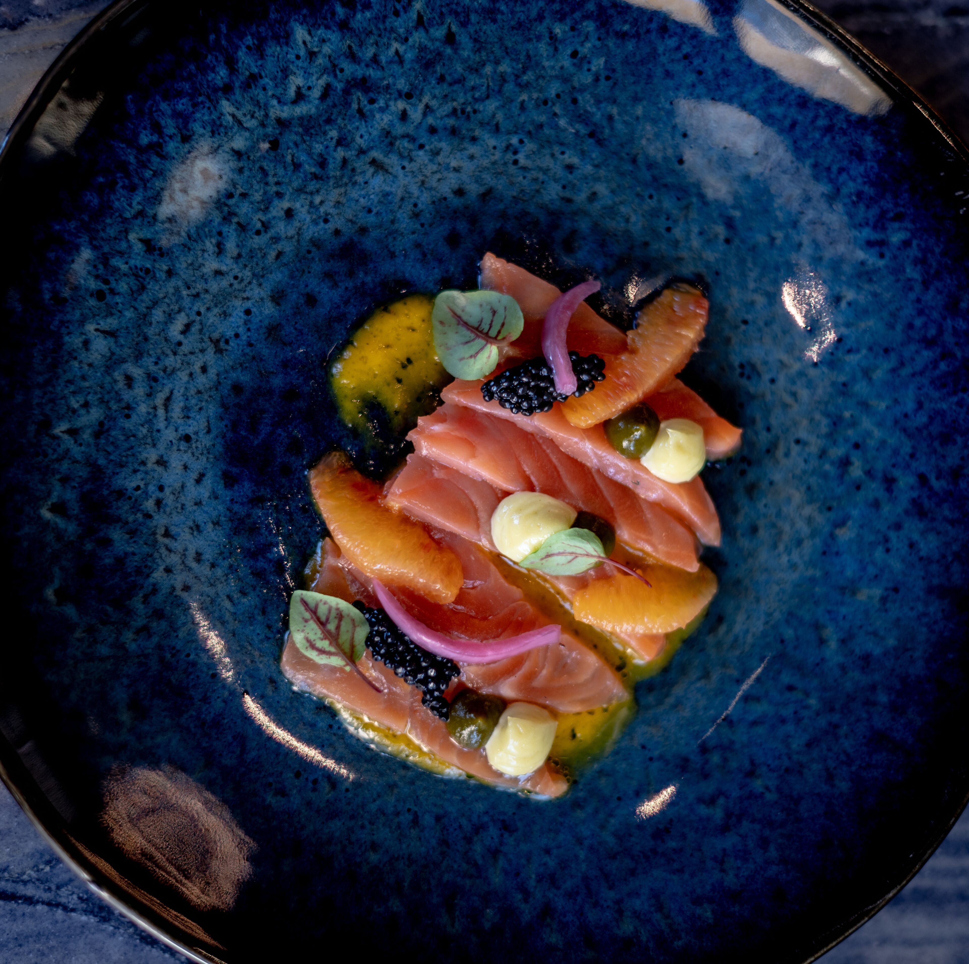 A blue ceramic plate with a seafood dish.