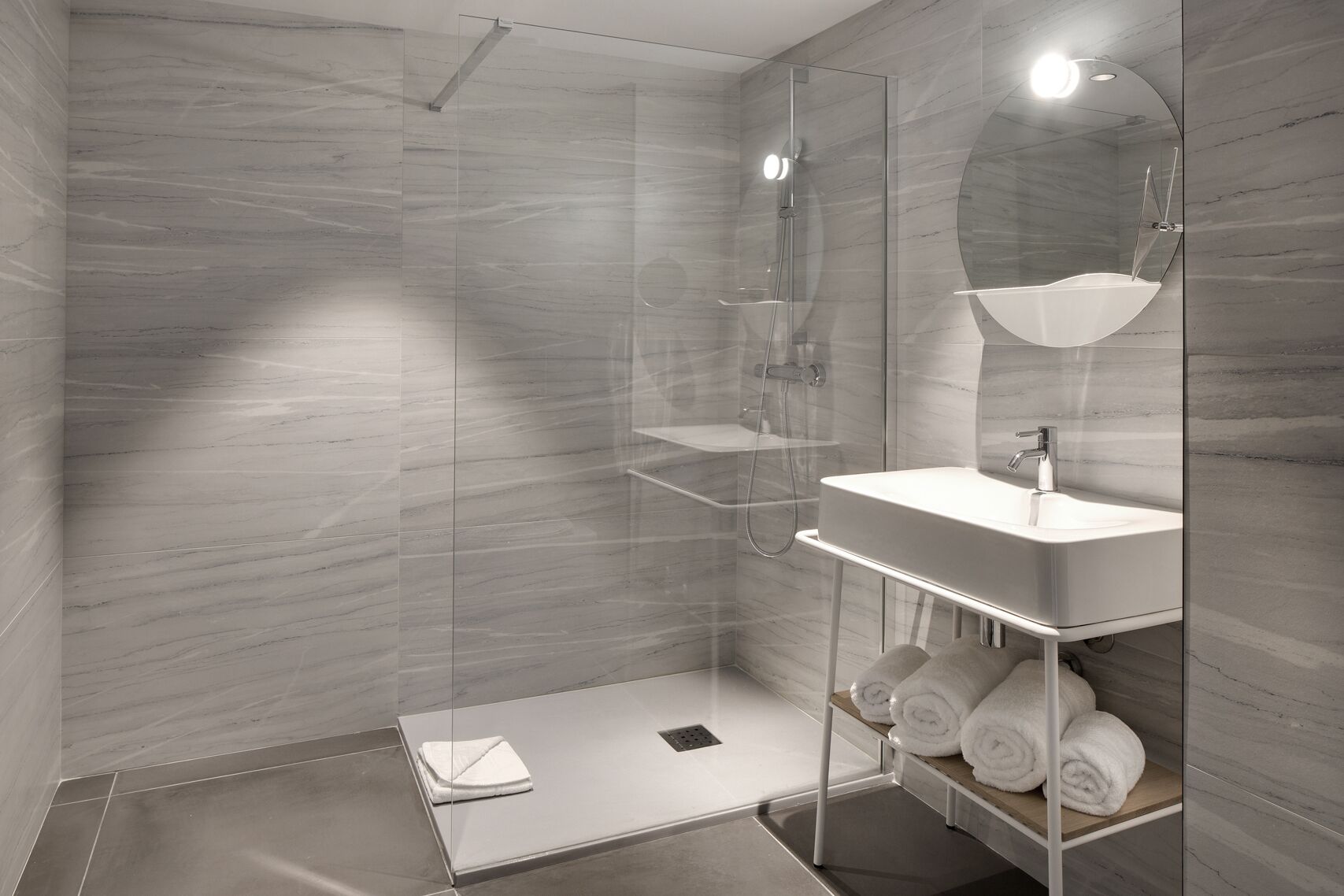 A modern bathroom with a glass-enclosed shower, a white sink, and a mirror.