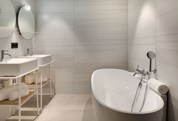 A modern bathroom with a freestanding bathtub, two sinks, and a towel rack. - Teritoria - Château Fage Hôtel (Arveyres)