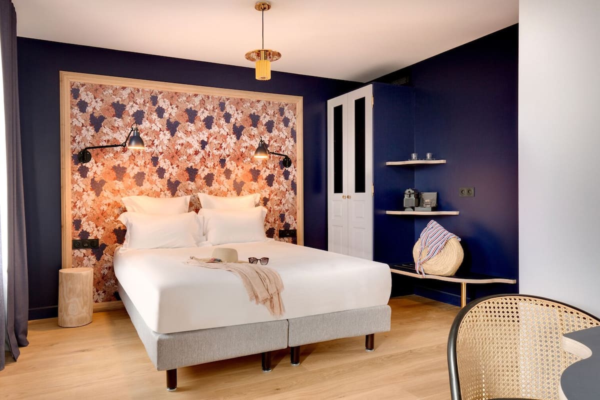 A bedroom with a large bed, a bedside table, a chair, and a wardrobe.