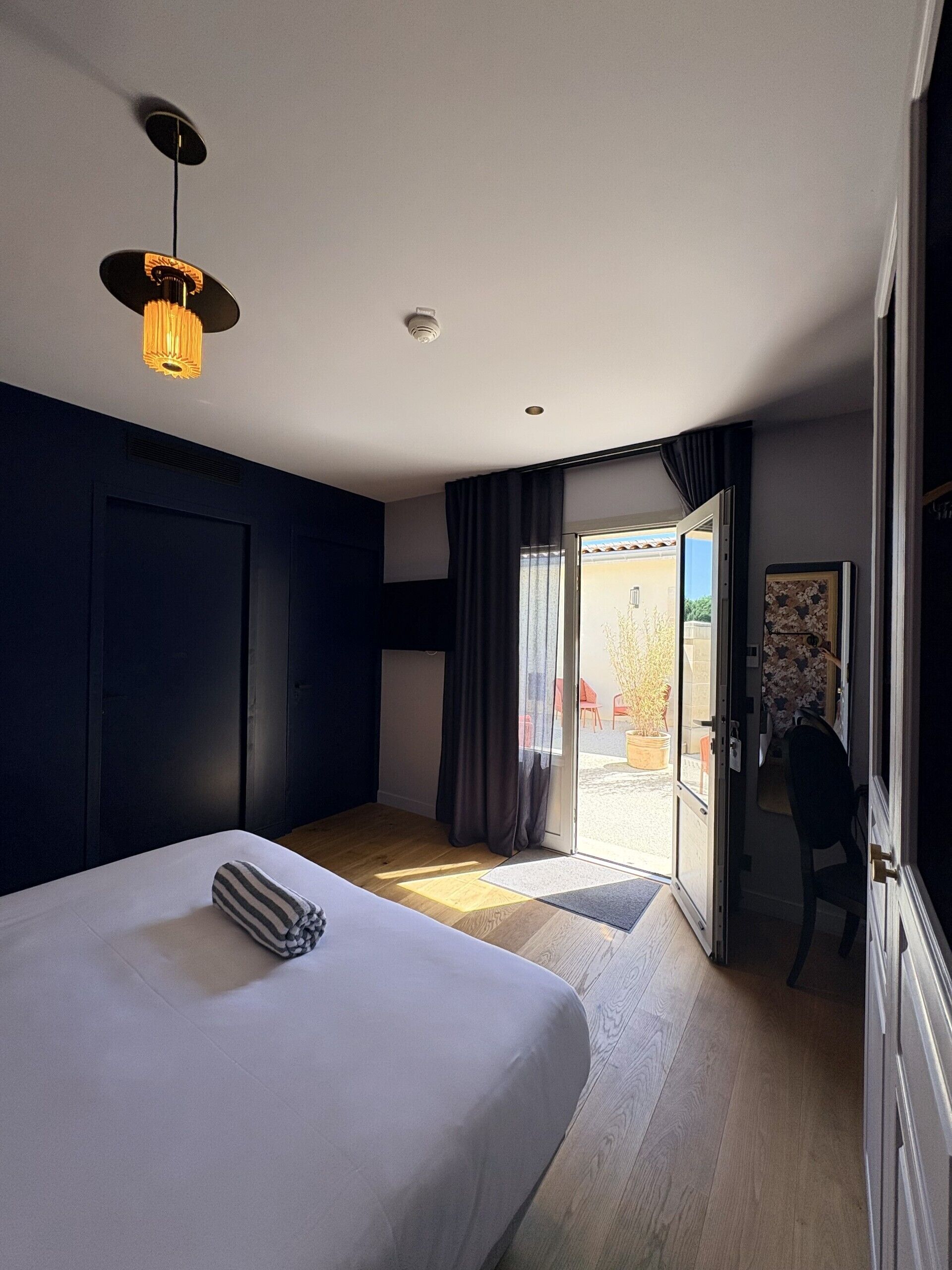 Habitación de hotel con una cama grande, una lámpara en el techo, una puerta que da a un espacio exterior y vistas al exterior.