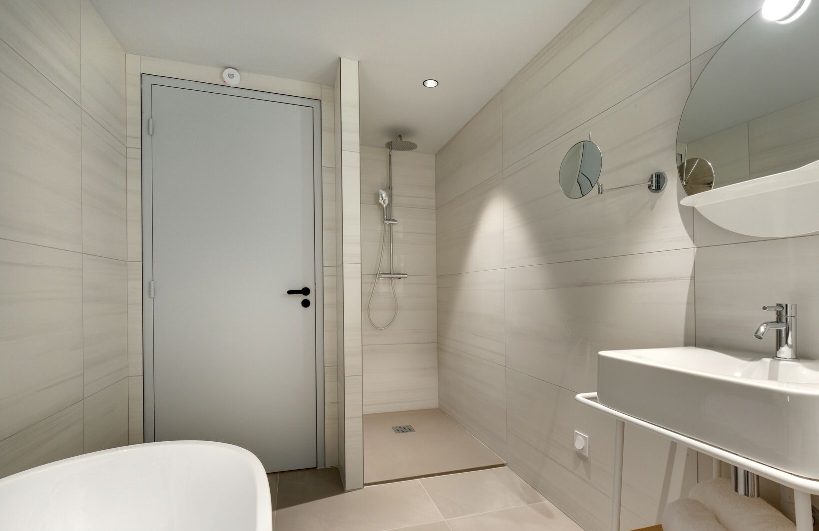 Un baño moderno con ducha, lavamanos e inodoro.