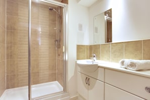 Bathroom features a glass-enclosed shower area and a sink with a mirror above.