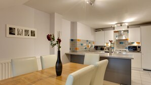 A modern kitchen with a central island, white cabinetry, and a tiled backsplash. - BookedUK - Penthouse 3 Bedroom Apartment (Bishop's Stortford)