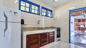 Eine Küche mit einem weißen Kühlschrank, Holzschränken, einer Arbeitsplatte aus Granit und einem Fenster mit blauer Umrandung.