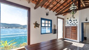Ein Zimmer mit großem Fenster und Blick auf ein Gewässer, einer hölzernen Bank und einem Fliesenboden.