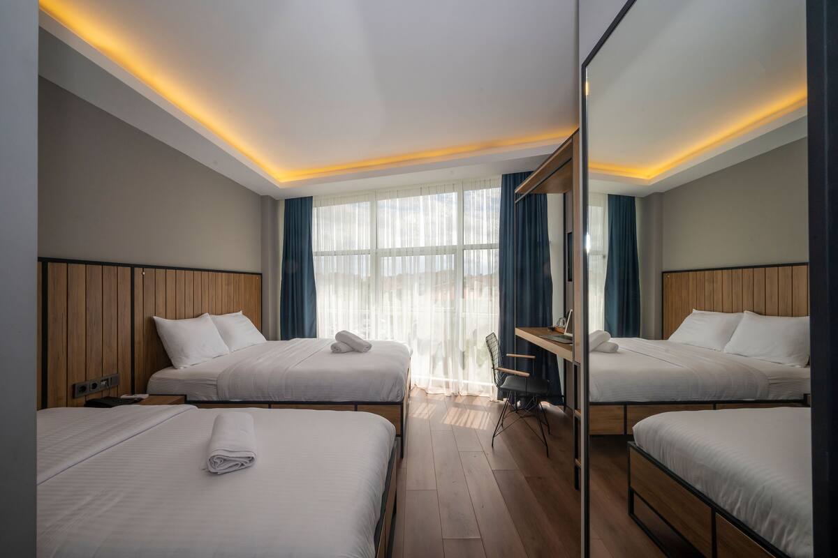 A hotel room with two beds, a desk, and a large mirror.