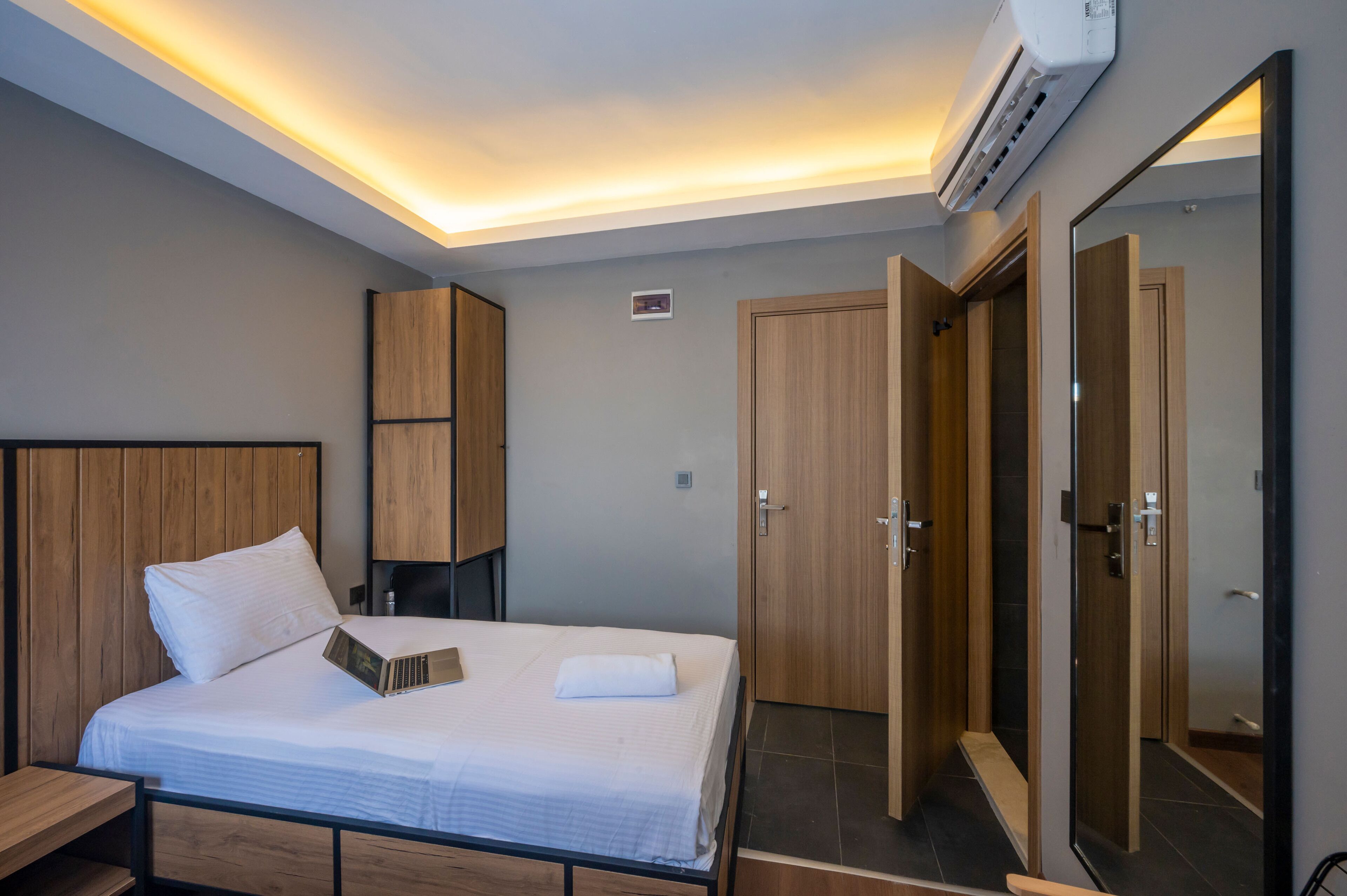 Een hotelkamer met een bed, nachtkastje, kledingkast en spiegel.