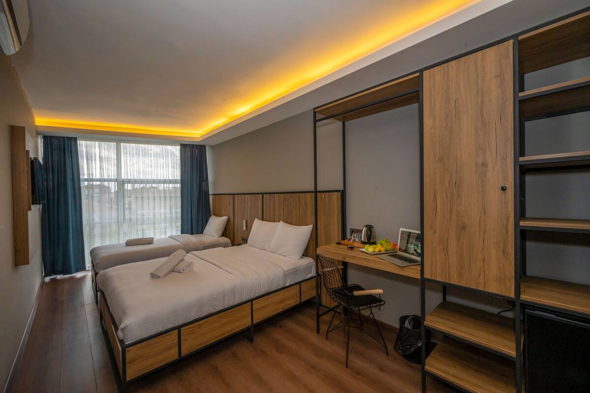 A modern hotel room with a large bed, a desk, and a wardrobe.