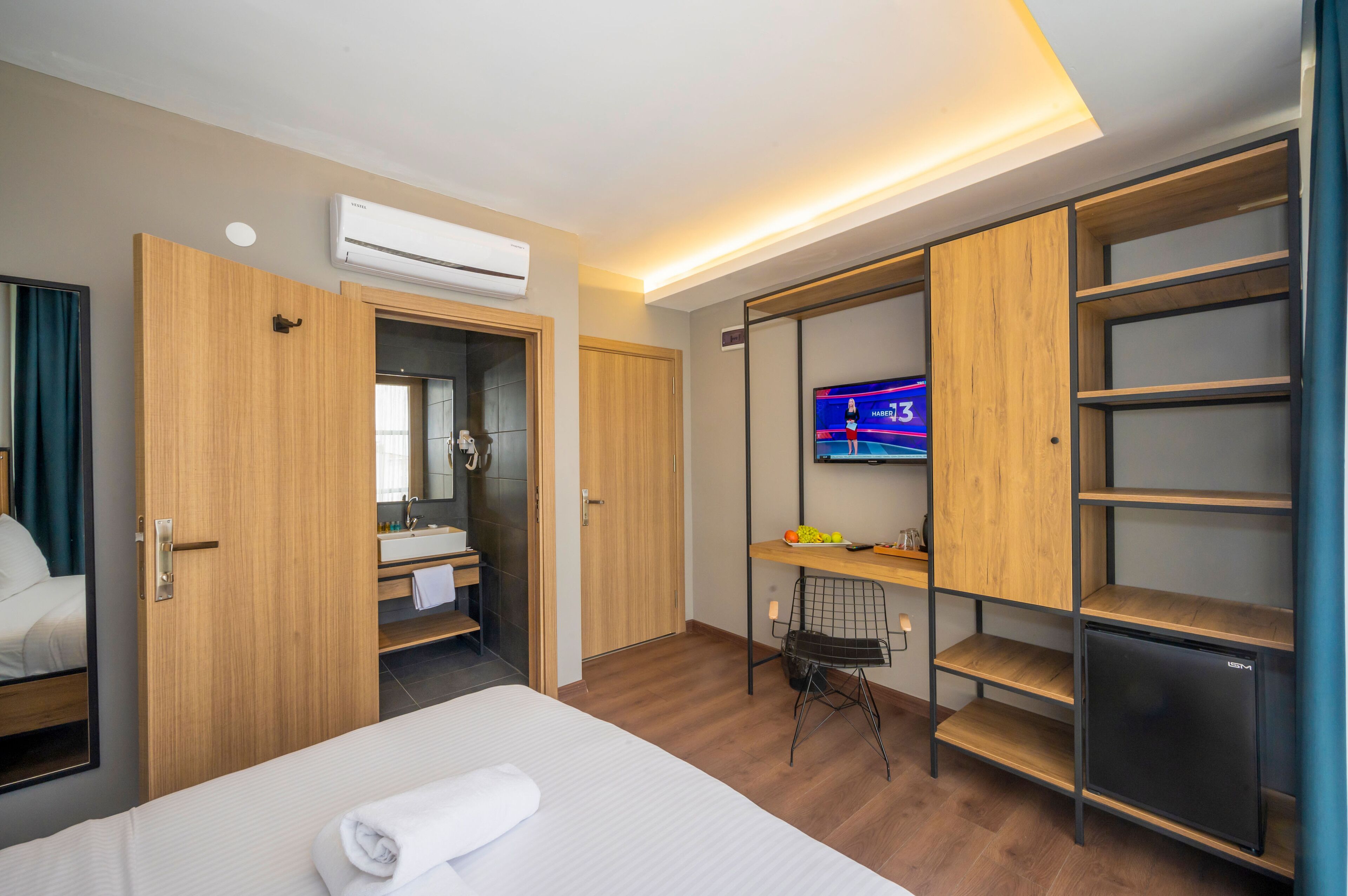 Una habitación de hotel con cama, televisor, escritorio y armario.