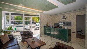 A lobby with a reception desk, seating area, and large windows overlooking a parking area. - Corlu Dem Hotel (Corlu)