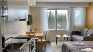 Una habitación de hotel moderna con kitchenette, una cama, un sofá y una pequeña mesa de comedor.