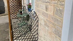 Eine Terrasse mit einem Metalltisch und -stühlen, einem Holzzapfen und einer Steinmauer.