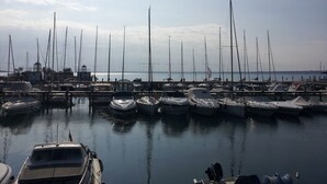 A marina with numerous boats docked, calm water, and a clear sky. - Direttamente Sulla Spiaggia, Vista Lago Impareggiabile (Moniga del Garda)