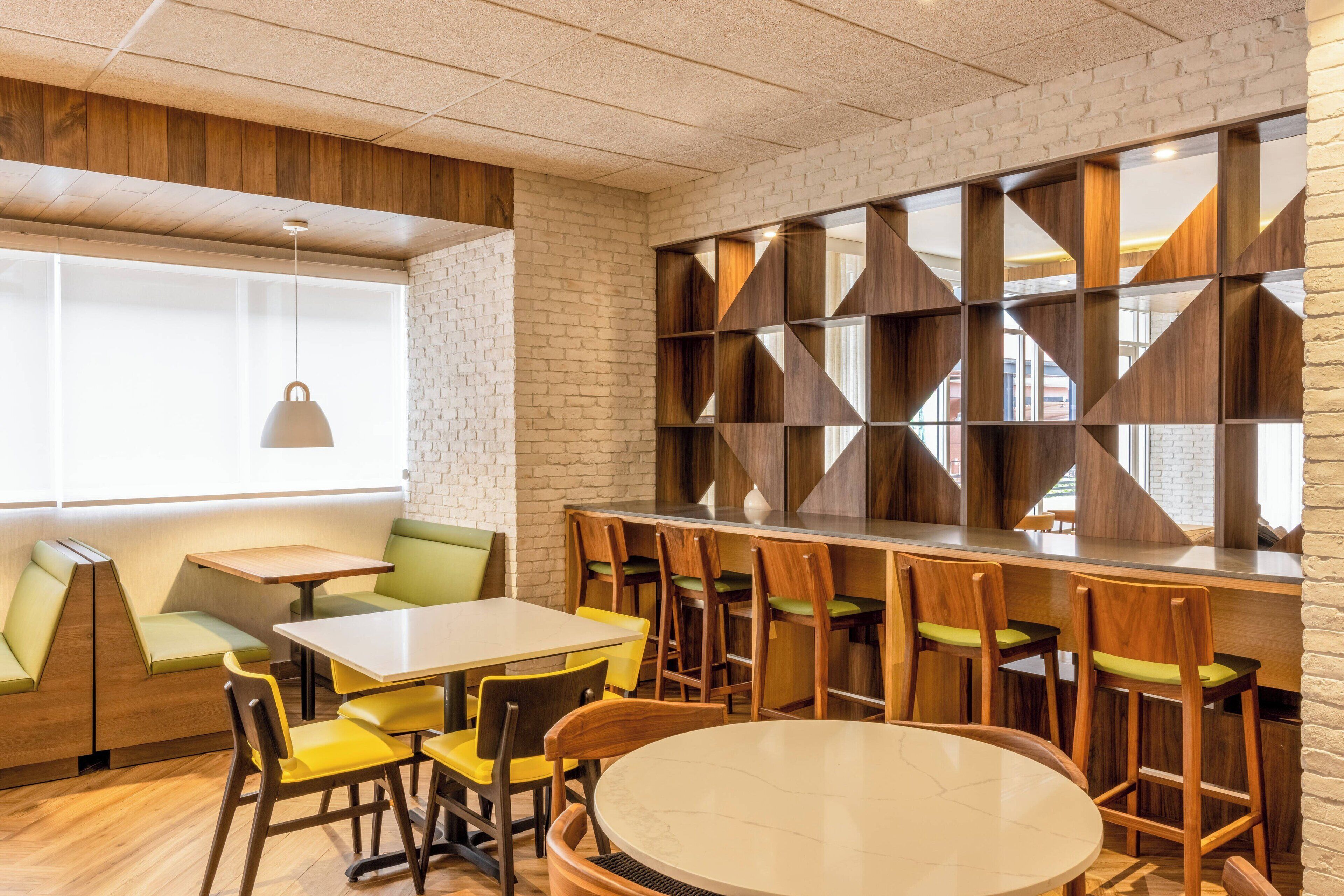 A modern restaurant with wooden furniture, a brick wall, and a large window.