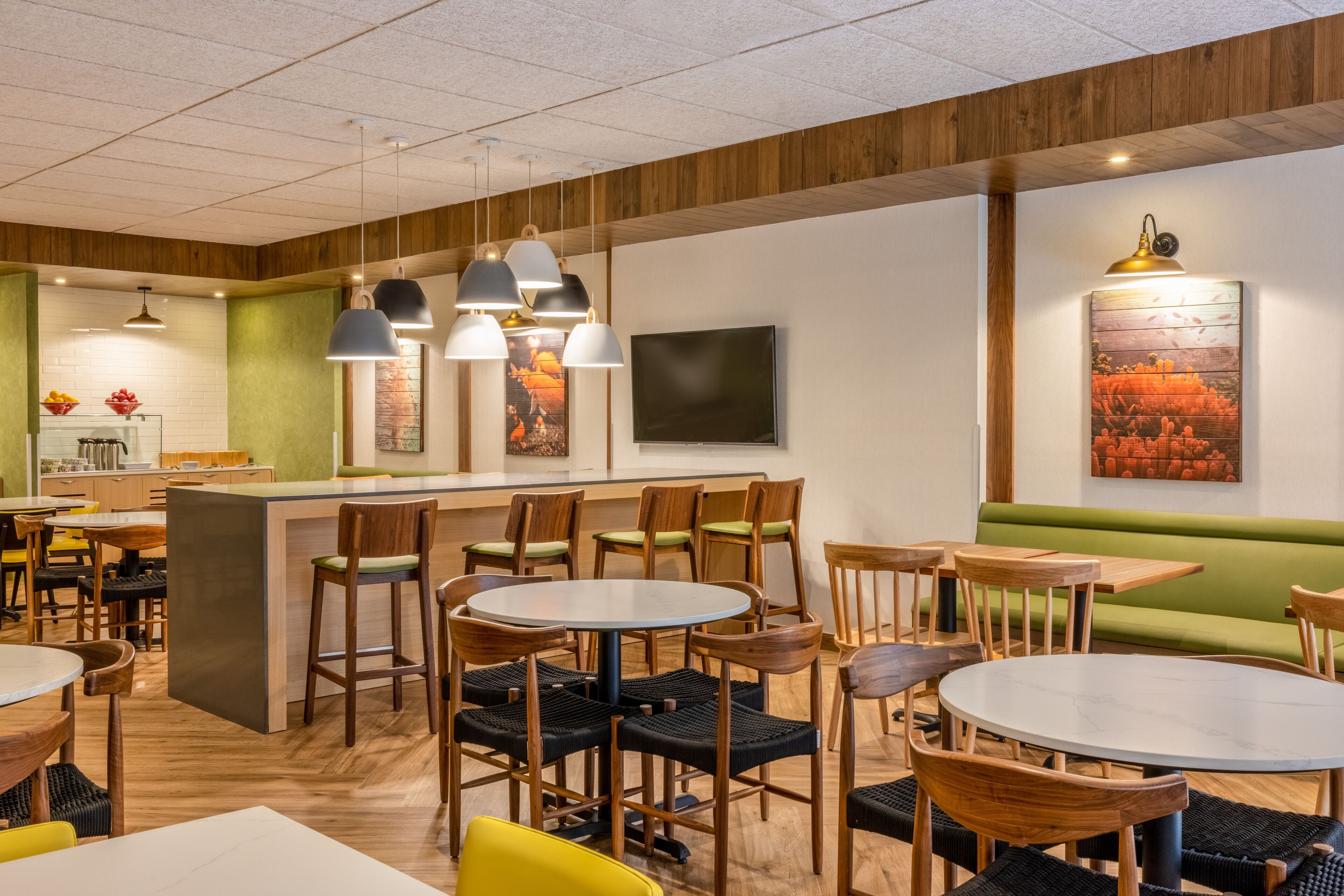 A restaurant interior with round tables, wooden chairs, and hanging pendant lights.