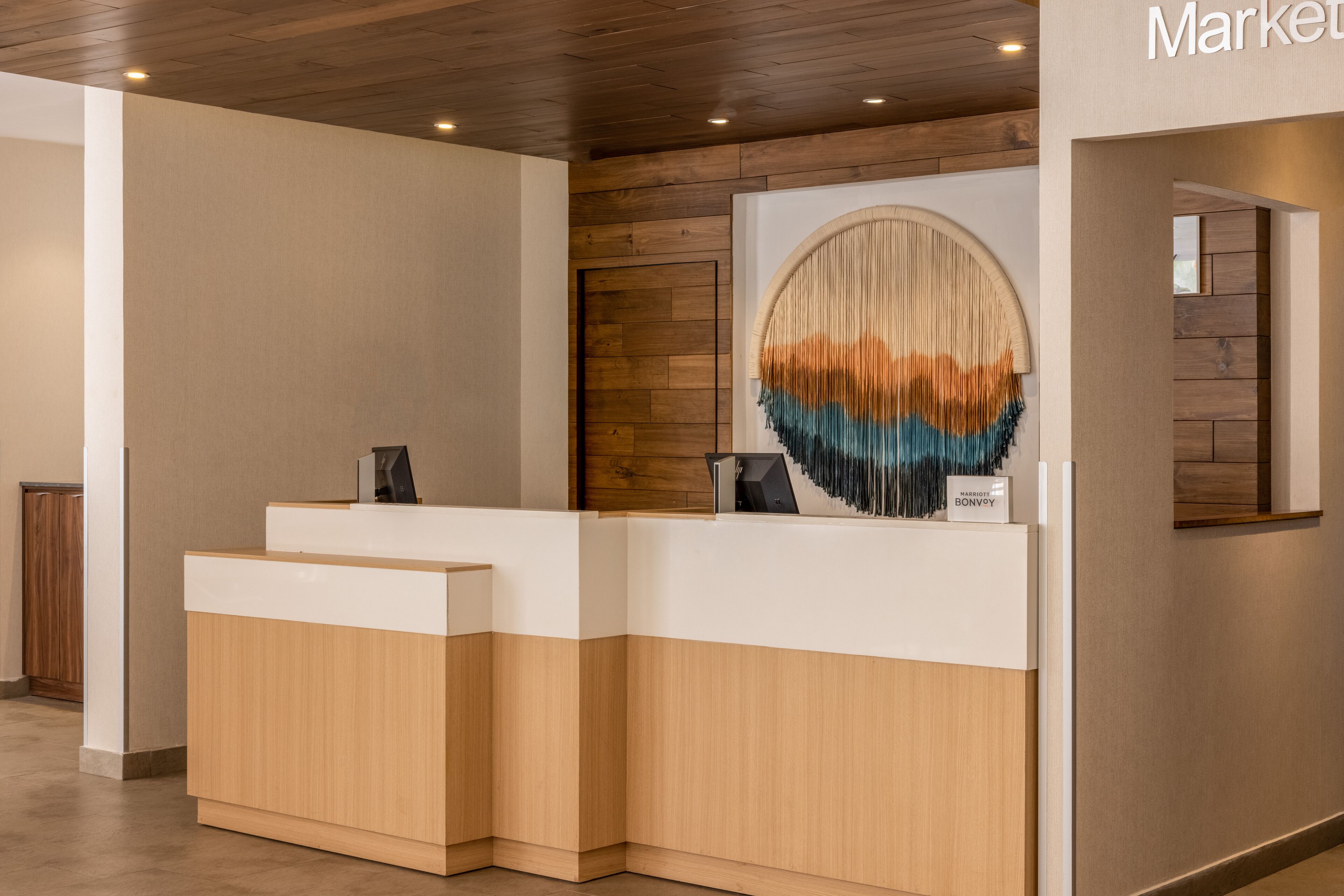 A reception desk with a wooden finish and a modern design, featuring a large, circular artwork on the wall behind it.