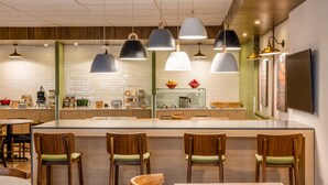 Un restaurante moderno con una isla central, asientos en la barra e iluminación colgante.