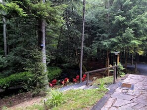 A forested area with a stone pathway leading to red chairs.