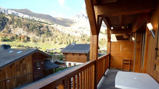 Une cabane en bois dotée d’un balcon donnant sur un paysage montagneux.