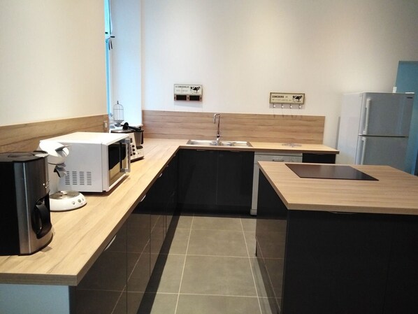 A modern kitchen with a microwave, coffee maker, and a sink.