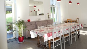 A dining area with a long table, chairs, a potted plant, a dresser, and pendant lights. - Charming Countryside Retreat with Modern Comforts near Hiking Trails and Lakes (Uriménil)