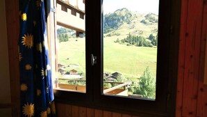 A room with a window overlooking a rural landscape, wooden walls, and a radiator. - Comfortable 40m² apartment for 6 near ski slopes, large terrace (Le Grand-Bornand)