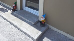 Una casa con una porta bianca e una piccola statuina di gnomo da giardino sugli scalini.