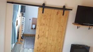 Una stanza con una porta scorrevole in legno, una televisione a muro e pavimento in legno.