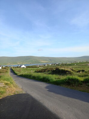 A rural road curving through a landscape with rolling hills, a body of water, and scattered houses. - Country Cottage Apartment, Valentia Island, Kerry (Valentia Island)