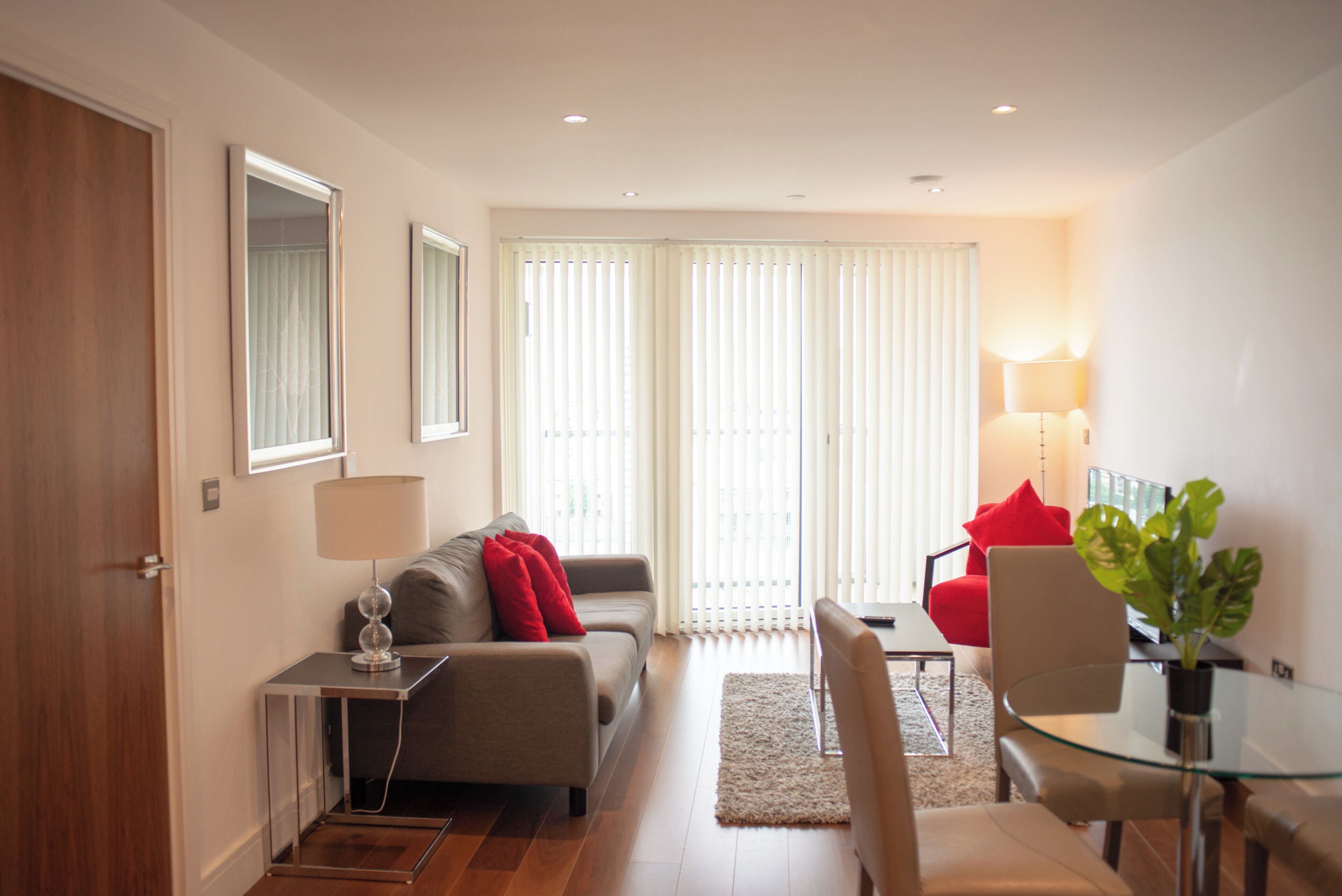 A modern living room with a sofa, a glass table, and a red chair.