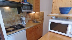 A compact kitchen with a stove, microwave, coffee maker, and a sink. - Bright Savoyard studio with south-facing balcony (Le Grand-Bornand)