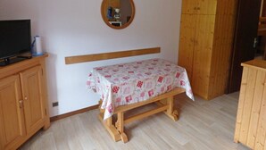 A small room with a wooden bed, a television on a cabinet, and a wardrobe. - Bright Savoyard studio with south-facing balcony (Le Grand-Bornand)