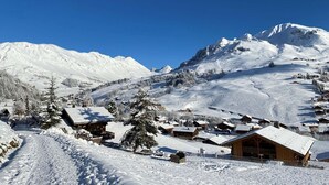 A snow-covered mountain village with wooden buildings and a clear blue sky. - Bright Savoyard studio with south-facing balcony (Le Grand-Bornand)
