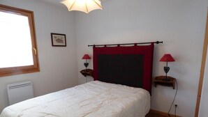 A bedroom with a bed, a window, a radiator, and two bedside lamps. - Mountain-Style Apartment for 6-7 Near Cable Cars and Town Center in Le Grand-Bornand (Le Grand-Bornand)