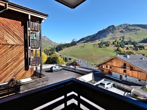 A wooden building with a balcony overlooking a valley with mountains and a clear sky.