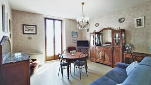 A dining area with a wooden table and chairs, a chandelier, and a large mirror cabinet.