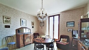 A dining area with a wooden table, chairs, a chandelier, and a television.