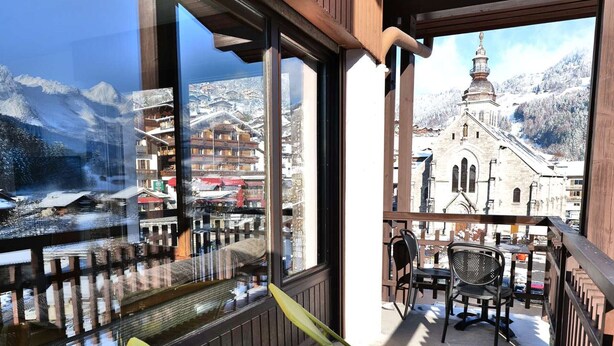Un balcon avec vue sur une montagne et une église.