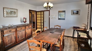 Une salle à manger avec une table et des chaises en bois, un buffet en bois et un lustre.