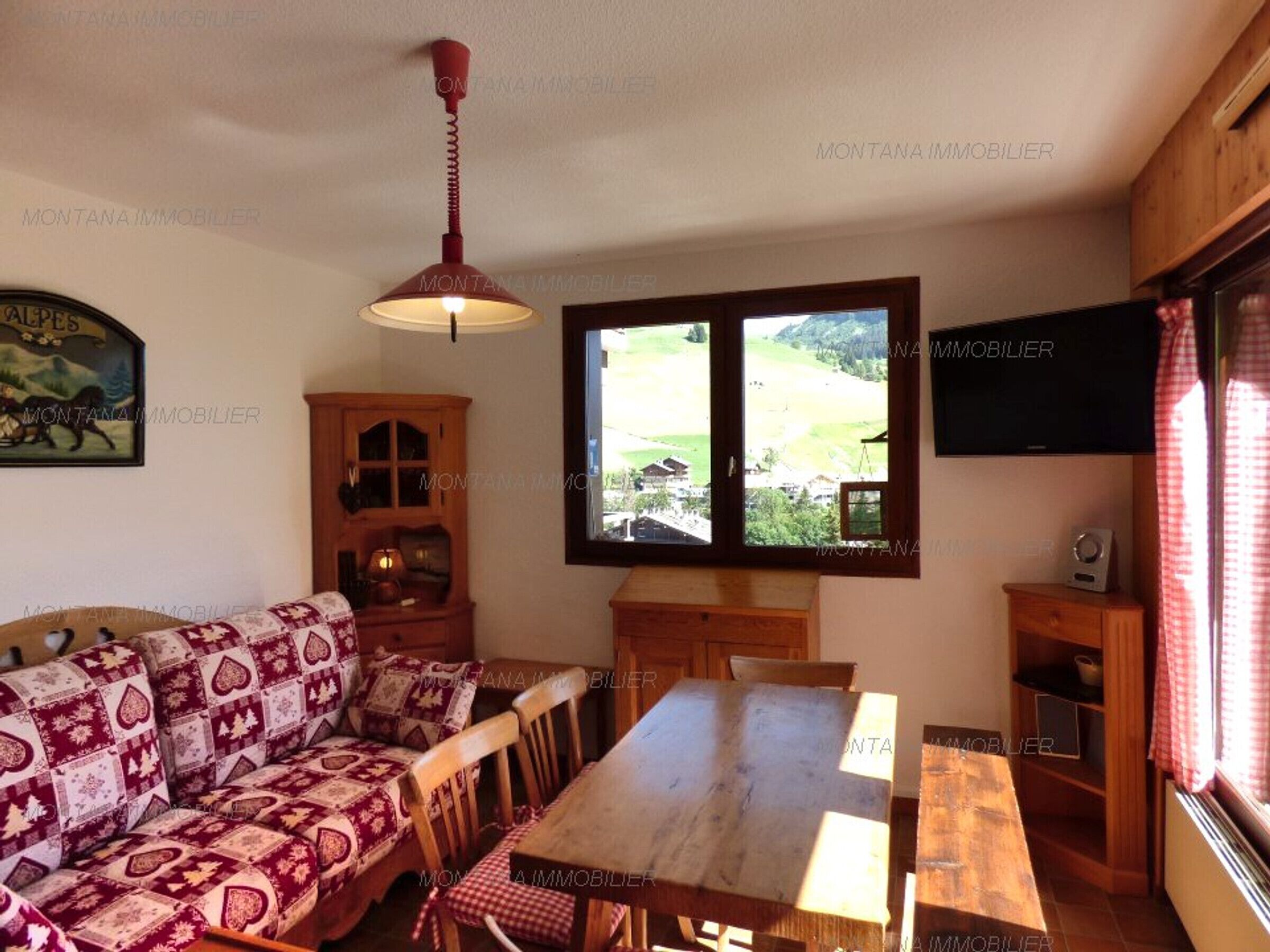 Een gezellige woonkamer met een bank, houten tafel en een raam met uitzicht op het platteland.